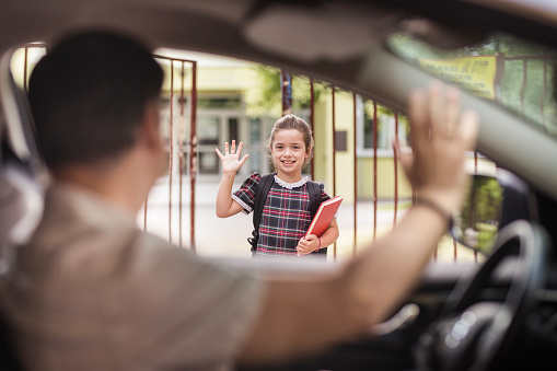 Man waving to child from inside car